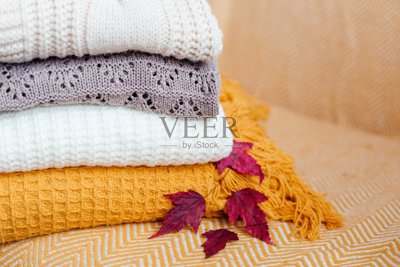 一堆柔软温暖的格子图案和一张秋叶特写。照片摄影图片