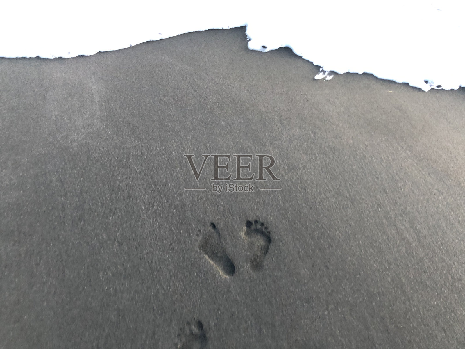 黑色沙滩上的脚印照片摄影图片