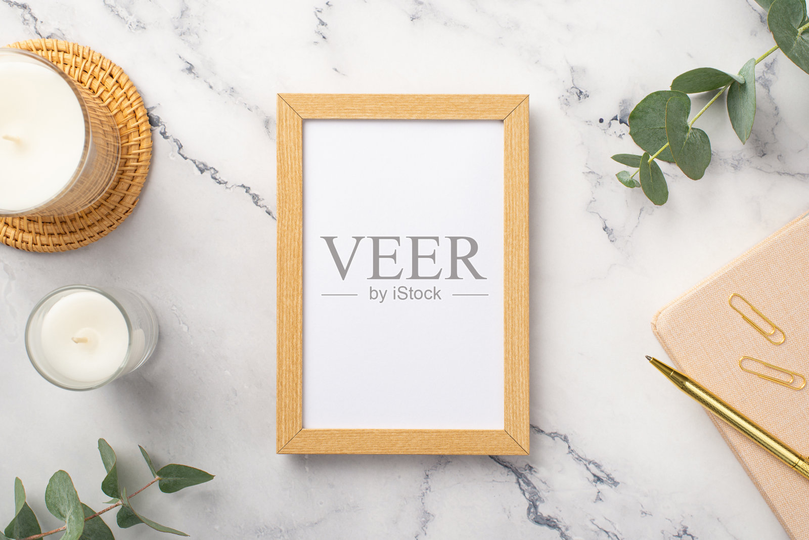 顶视图照片的木制相框蜡烛藤服务垫粉红色日记金钢笔夹子和桉树白色大理石背景与空白照片摄影图片