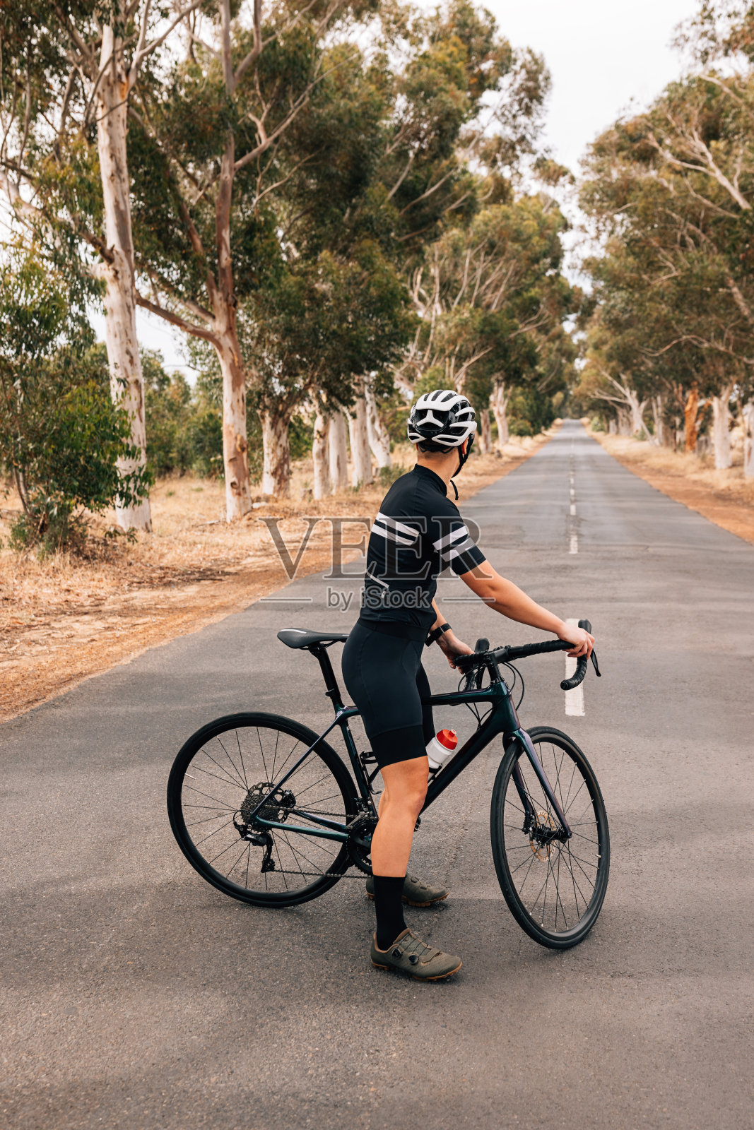 一个职业妇女骑自行车的背影站在空旷的乡村道路上准备骑照片摄影图片
