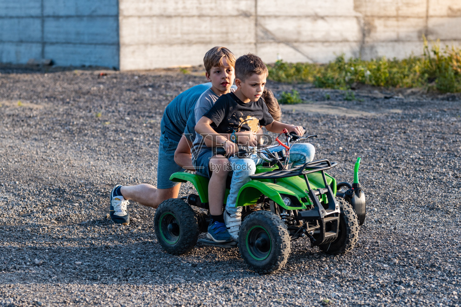 父亲推着他的两个儿子在四驱车上启动引擎照片摄影图片