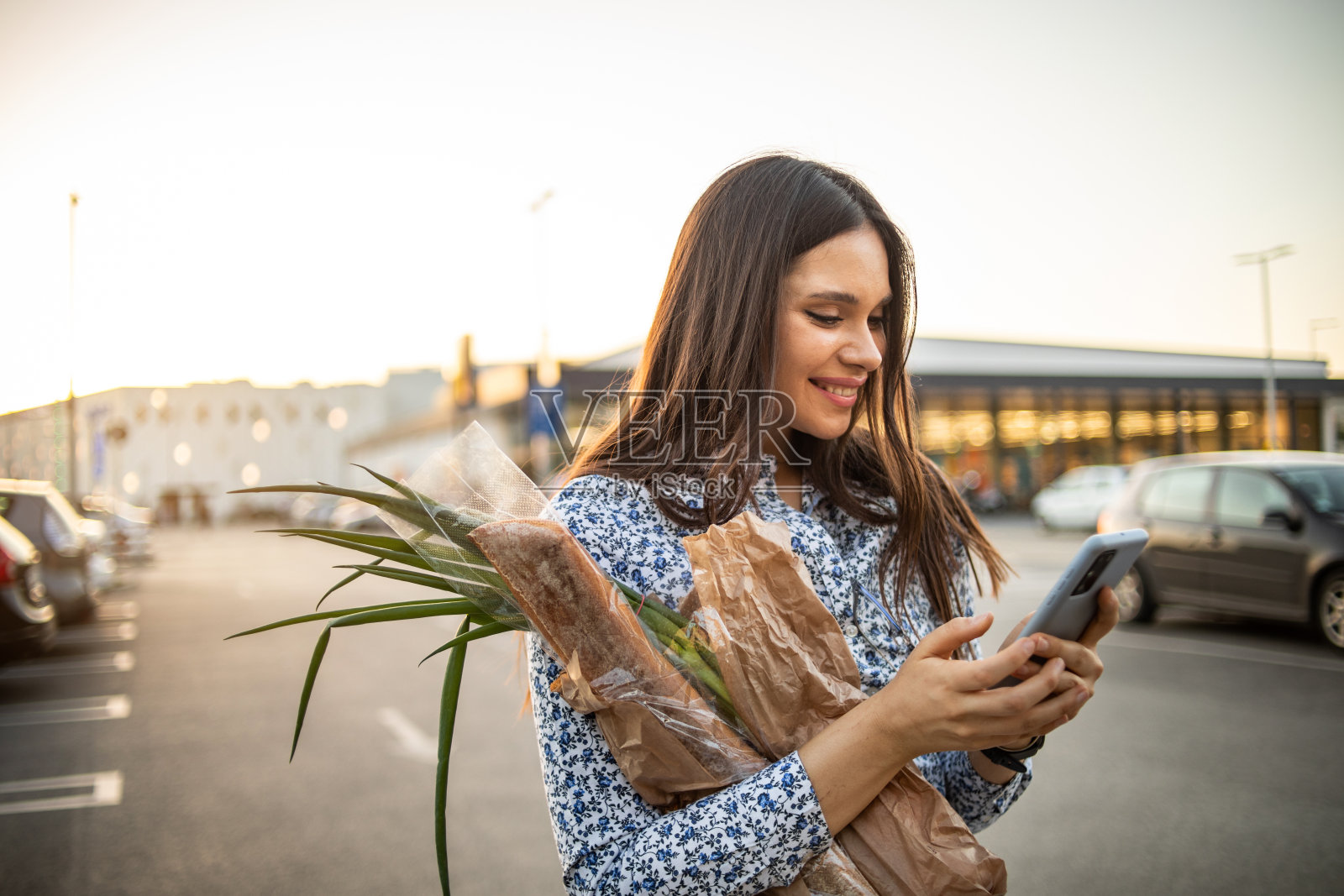 一个年轻漂亮的女人在超市买完东西，买了面包和蔬菜。照片摄影图片