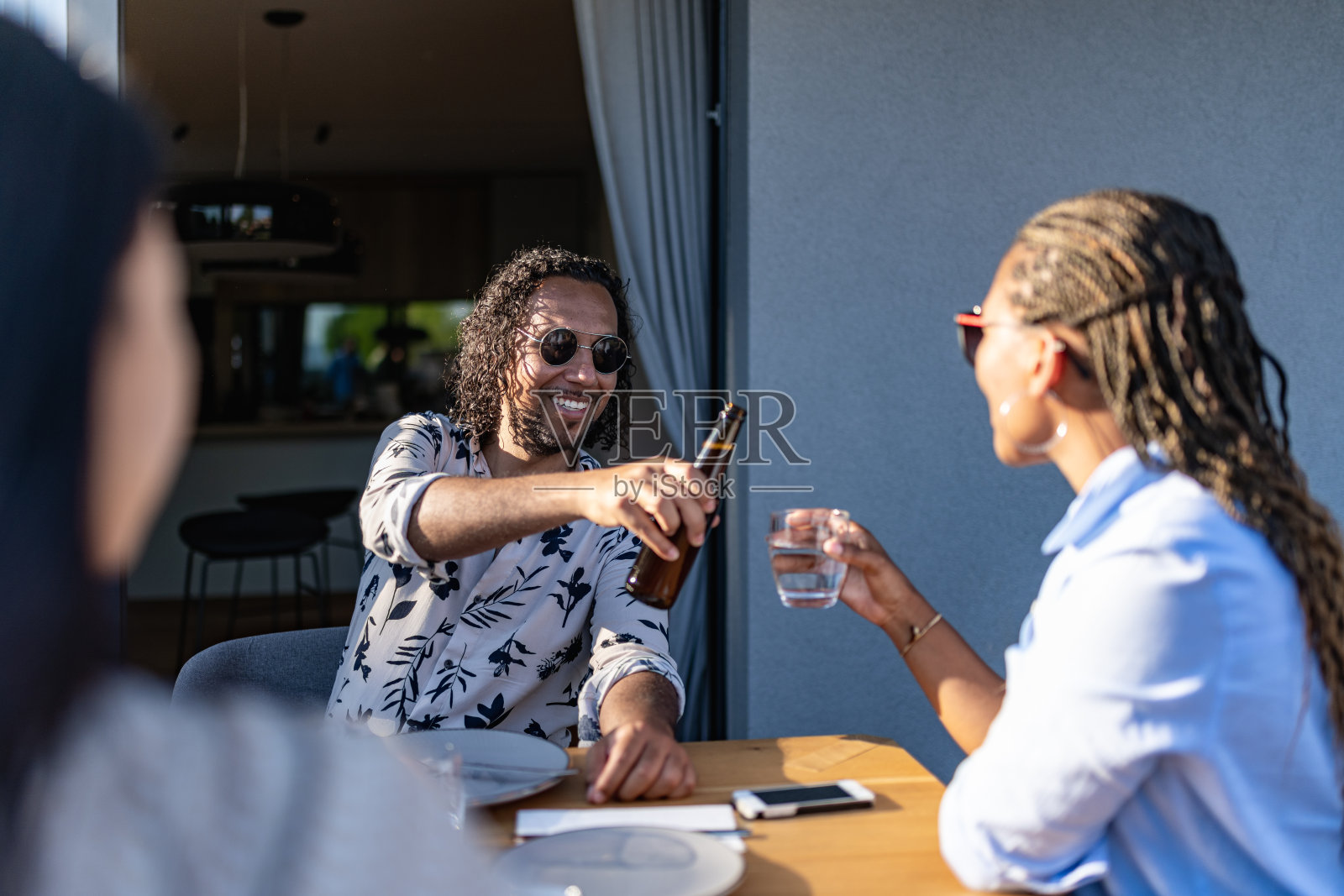 在一个炎热的夏夜，在新房子里与快乐的朋友举杯。国际多元化的民族。照片摄影图片