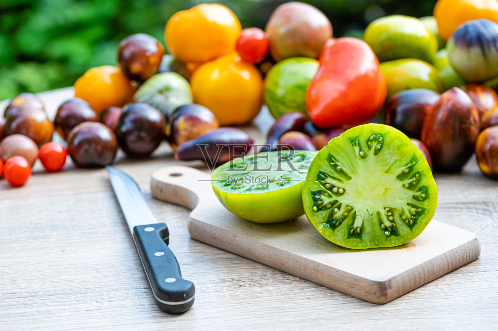 桌子上有一个切菜板，背景上有不同颜色的番茄照片摄影图片