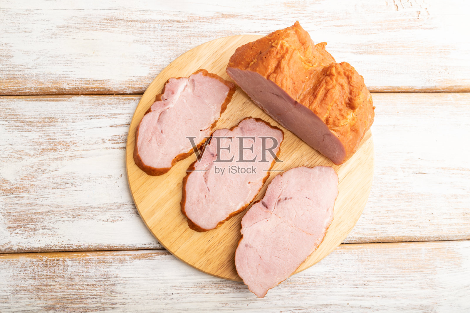 烟熏火腿放在砧板上，白色木制背景。俯视图，特写。照片摄影图片