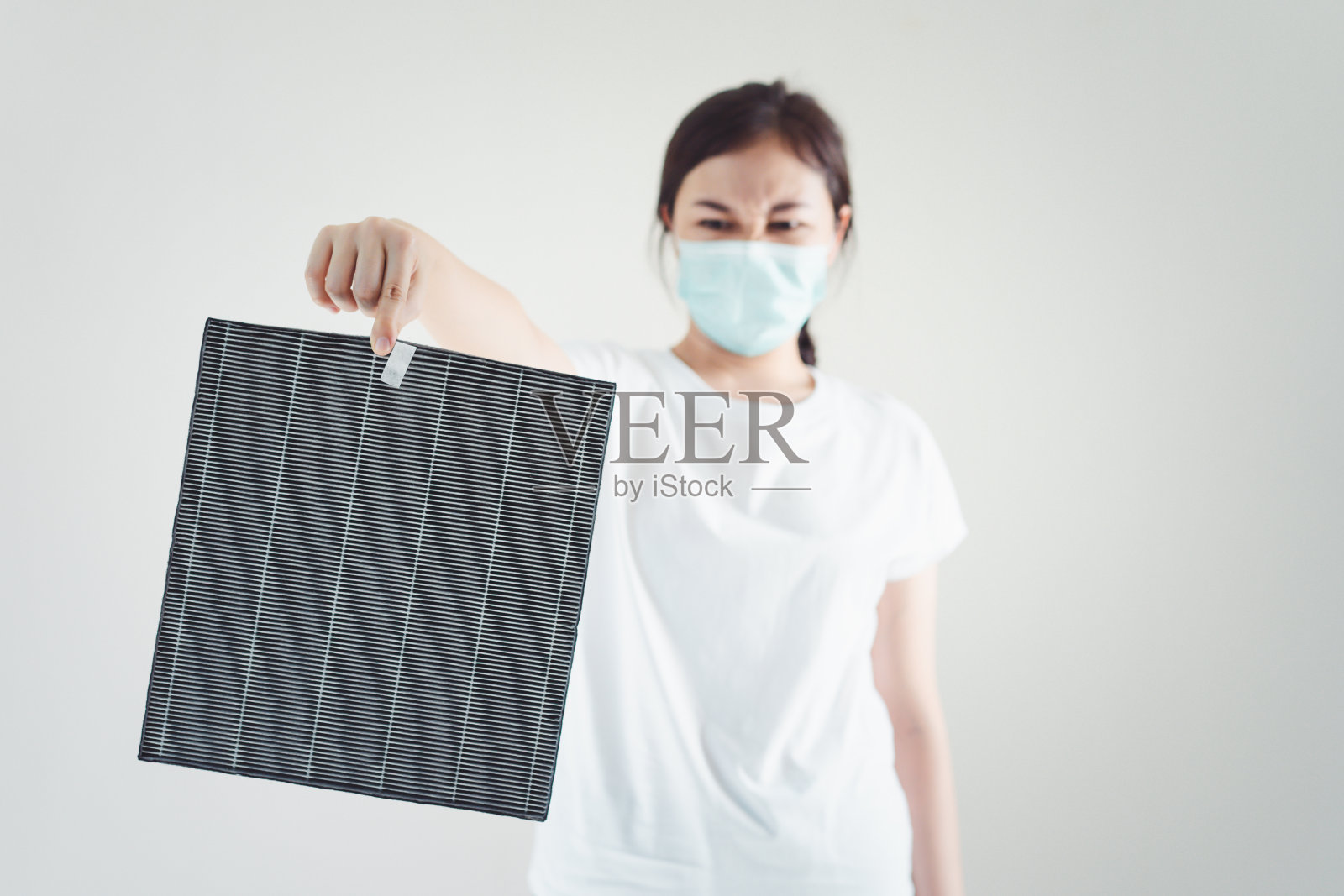 更换空气净化器过滤器的女人。照片摄影图片