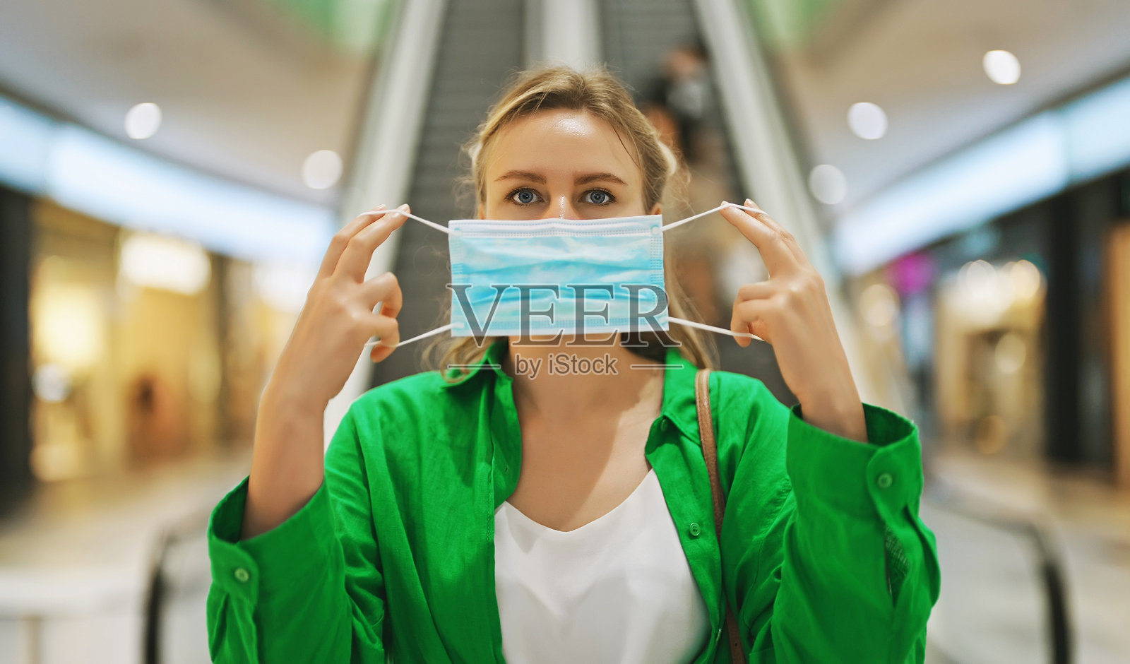 在商场里戴医用口罩的女人在公共场所戴口罩。照片摄影图片