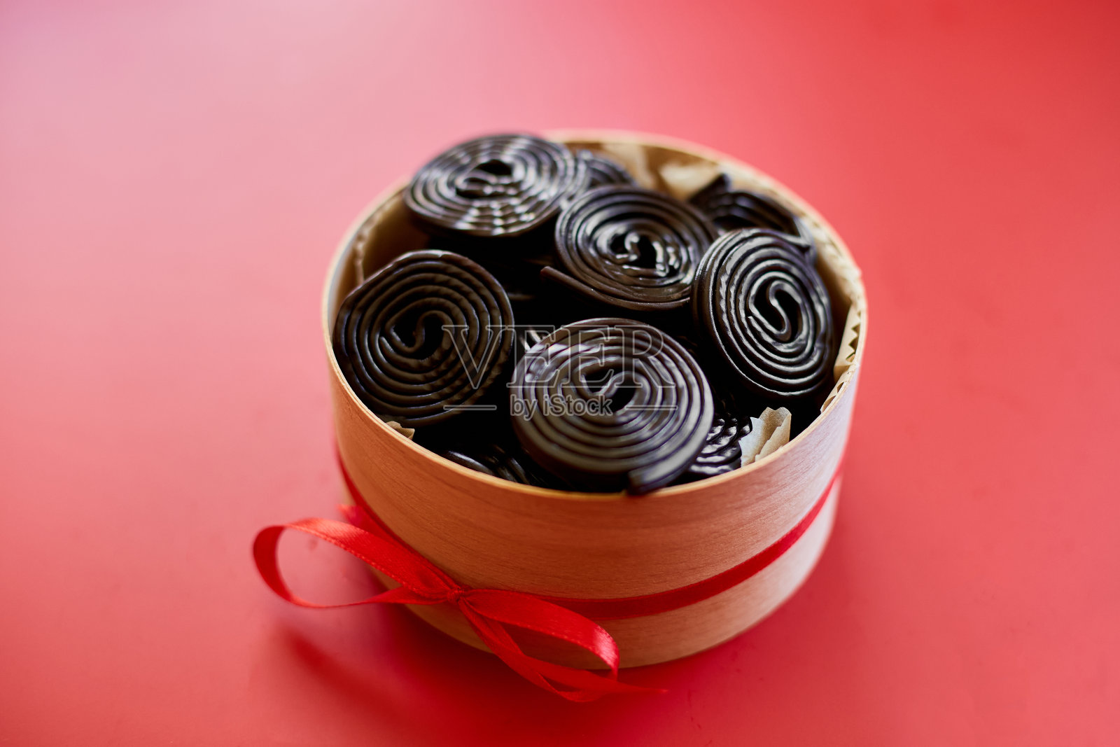 美味的黑色甘草糖果在红色背景的礼物盒，糖果味甘草，俯视图，复制空间。照片摄影图片