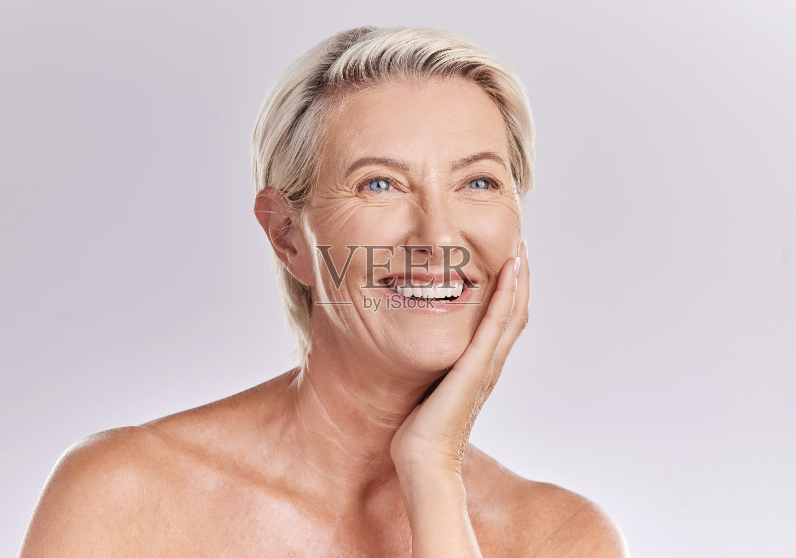 美丽成熟的白种人女人在摄影棚里裸露上身，与粉红色背景隔离。快乐的老年女性与发光的皮肤。良好的皮肤护理和健康的日常生活就是对皮肤的自我护理照片摄影图片