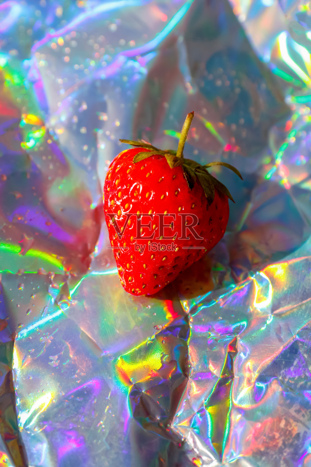 离焦特写一个成熟的红草莓对现代全息图背景。水果和浆果。收获和作物概念。有机食品。时髦的梯度。的焦点照片摄影图片