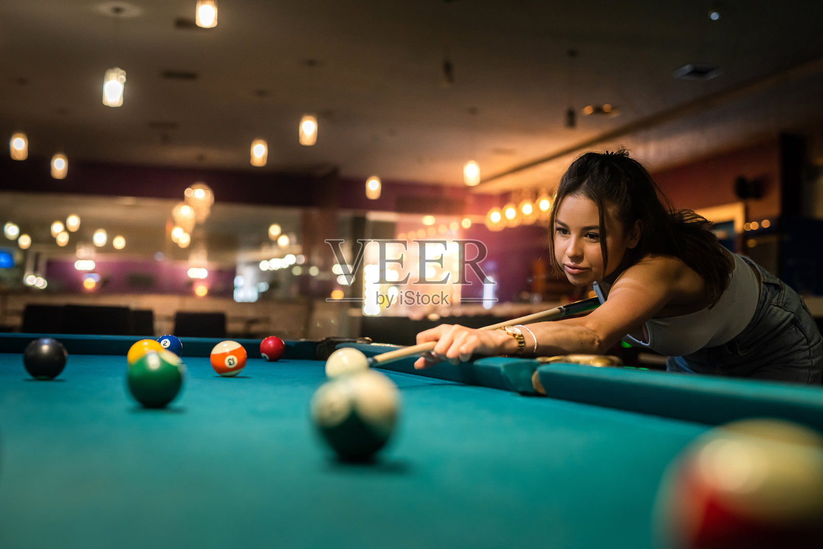 用球杆打台球和瞄准台球的女选手照片摄影图片