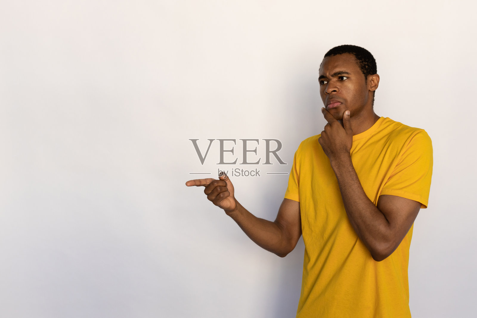 沉思的年轻人指着一边的肖像照片摄影图片