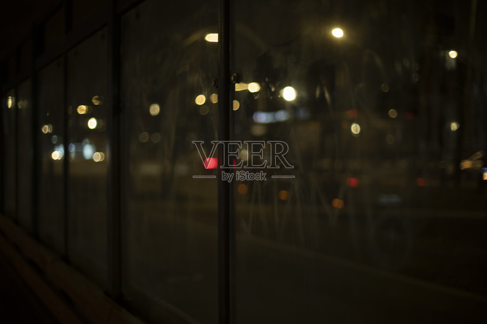 夜间道路上的灯光。模糊的背景通过玻璃在黑暗中。照片摄影图片