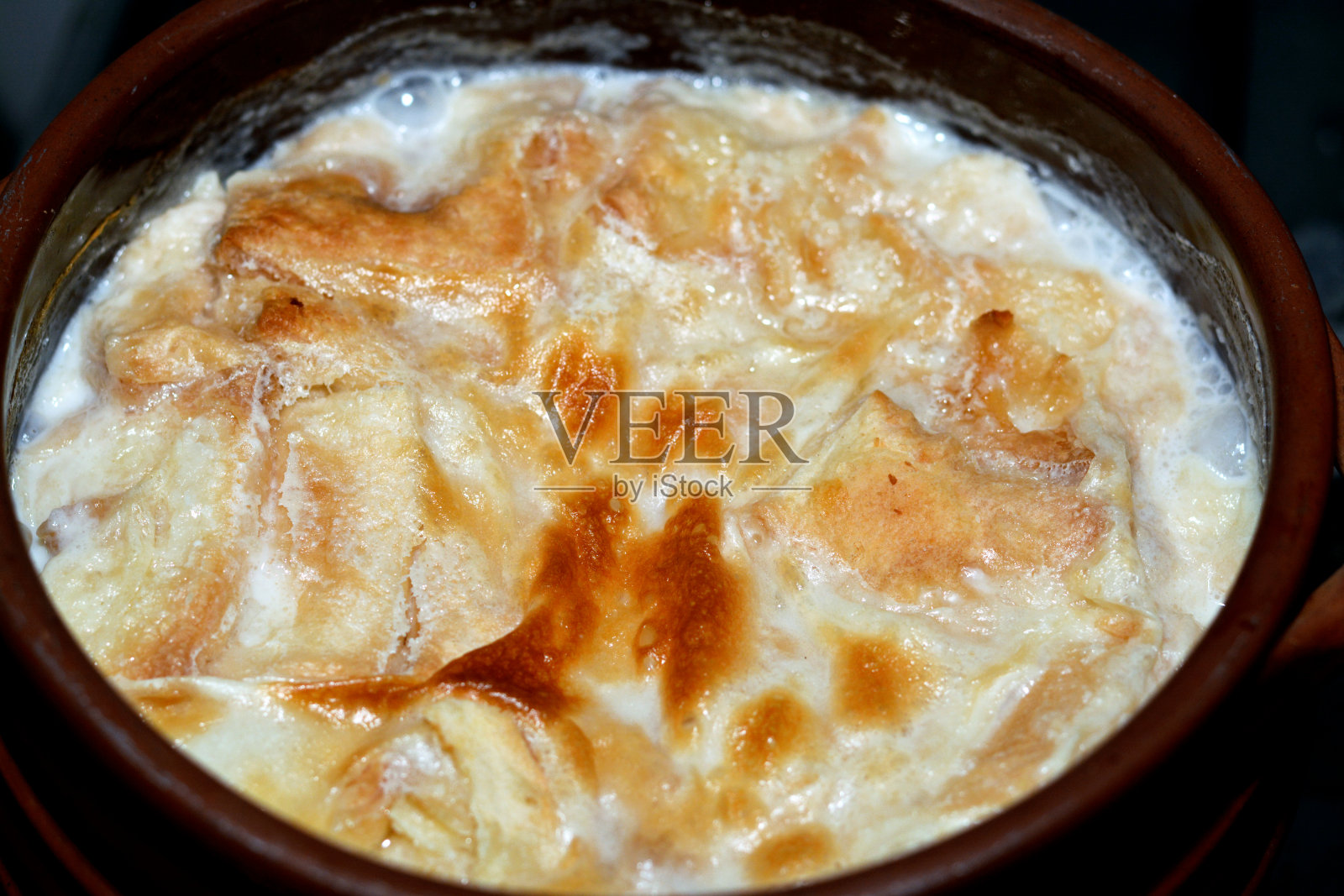 传统的阿拉伯埃及东部甜点被称为Om Ali，埃及面包布丁在一个棕色的碗陶器砂锅照片摄影图片