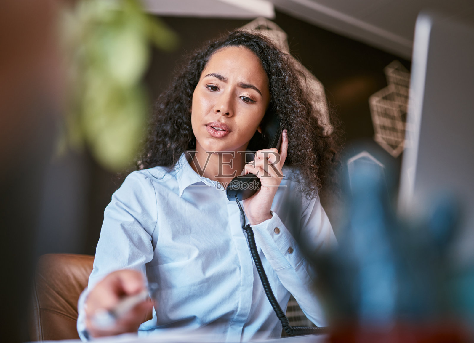 年轻的混血女商人在与客户打电话和阅读文件时感到困惑。西班牙企业家一边给客户打电话一边看文件照片摄影图片