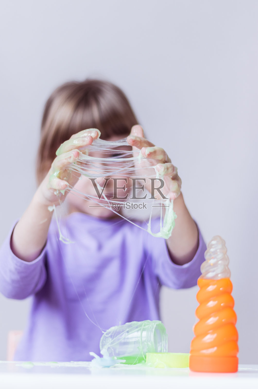 一个穿着淡紫色长袖的女孩用手伸开一张绿色黏液蜘蛛网照片摄影图片