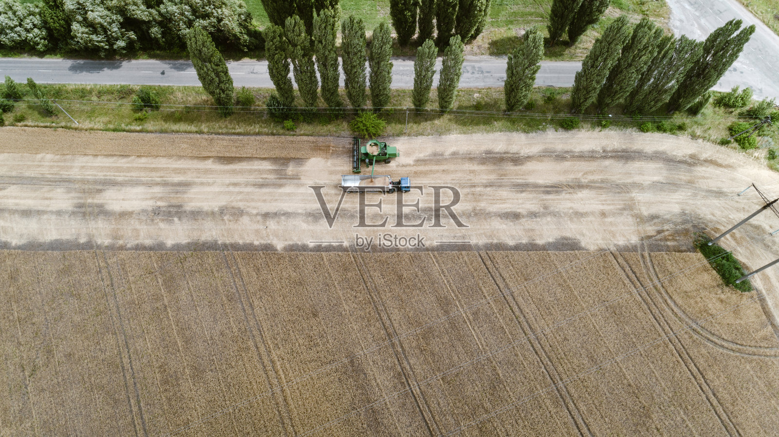 鸟瞰图与收割机倾倒作物到卡车拖车照片摄影图片