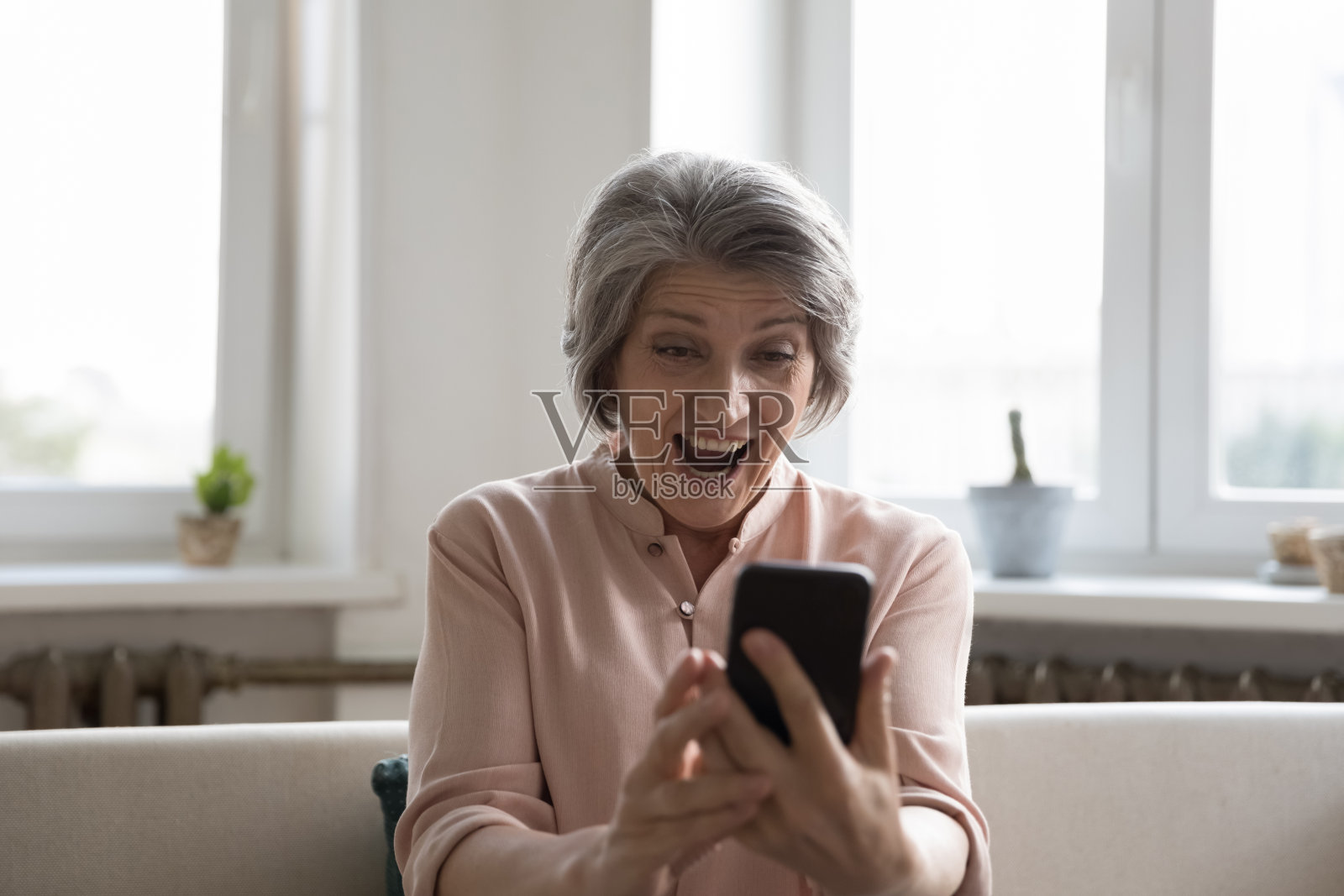 老年妇女张着嘴盯着手机屏幕照片摄影图片