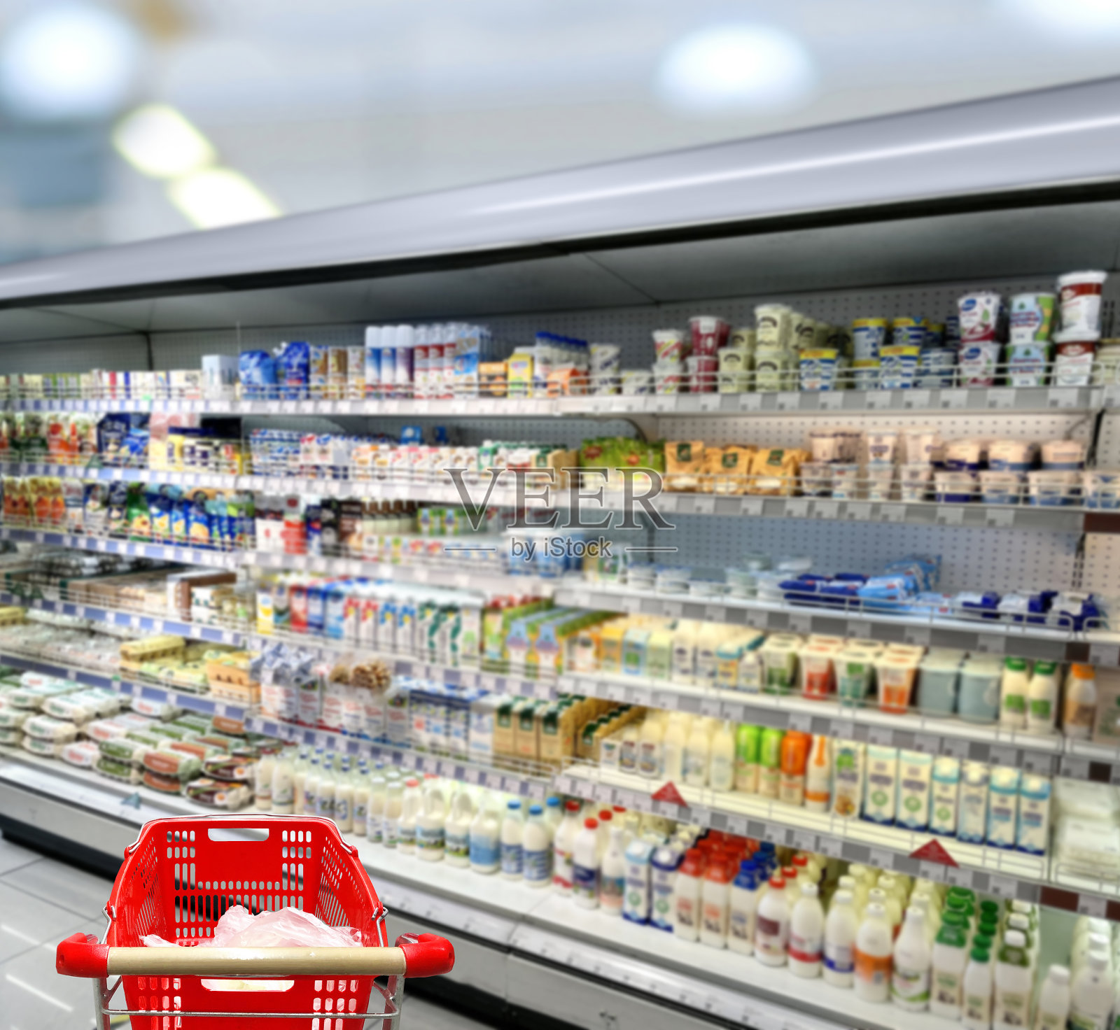 在超市挑选乳制品。空无一人的超市里的空购物车照片摄影图片