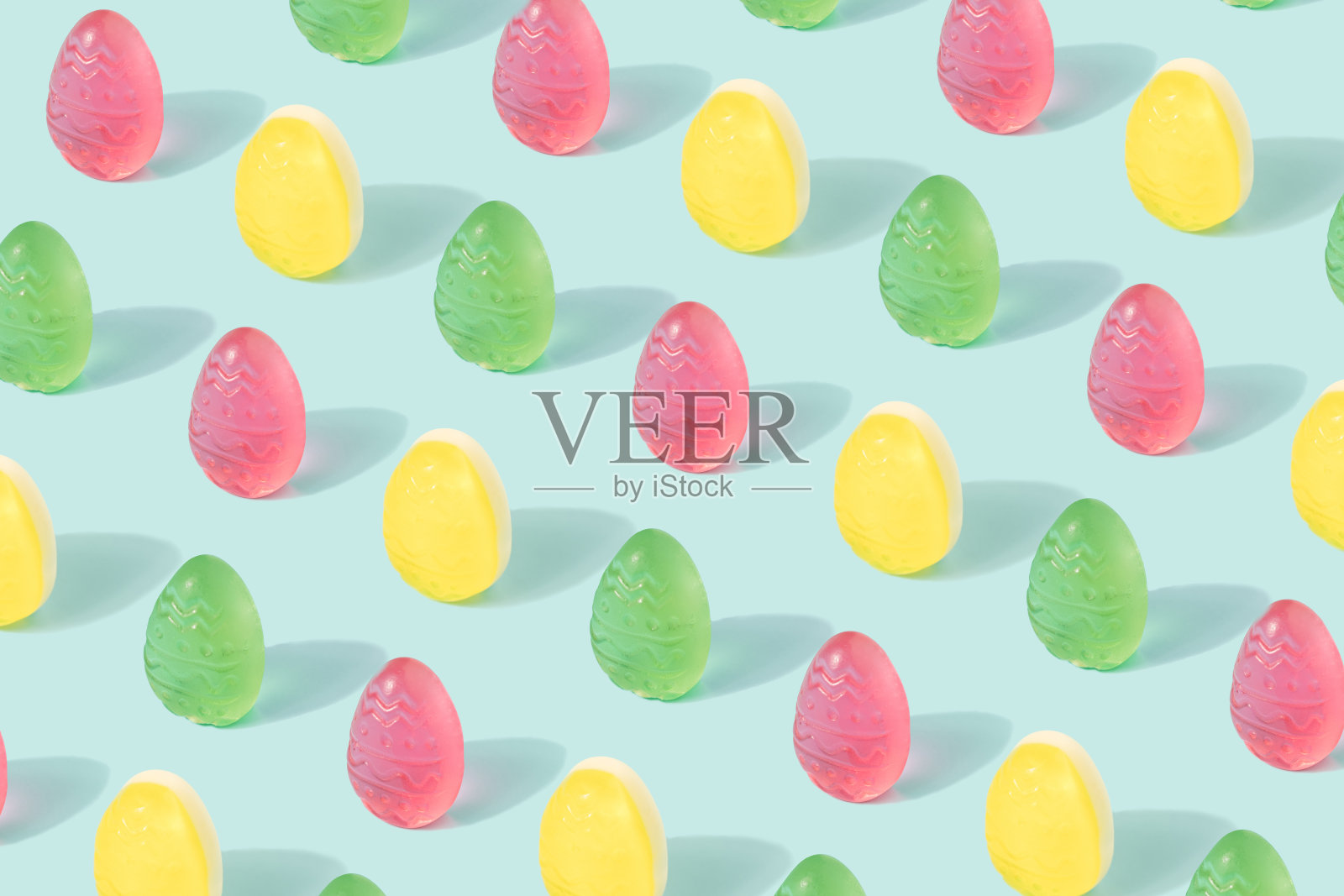复活节彩蛋图案与复制空间由彩色软糖在一个柔和的蓝色背景。照片摄影图片