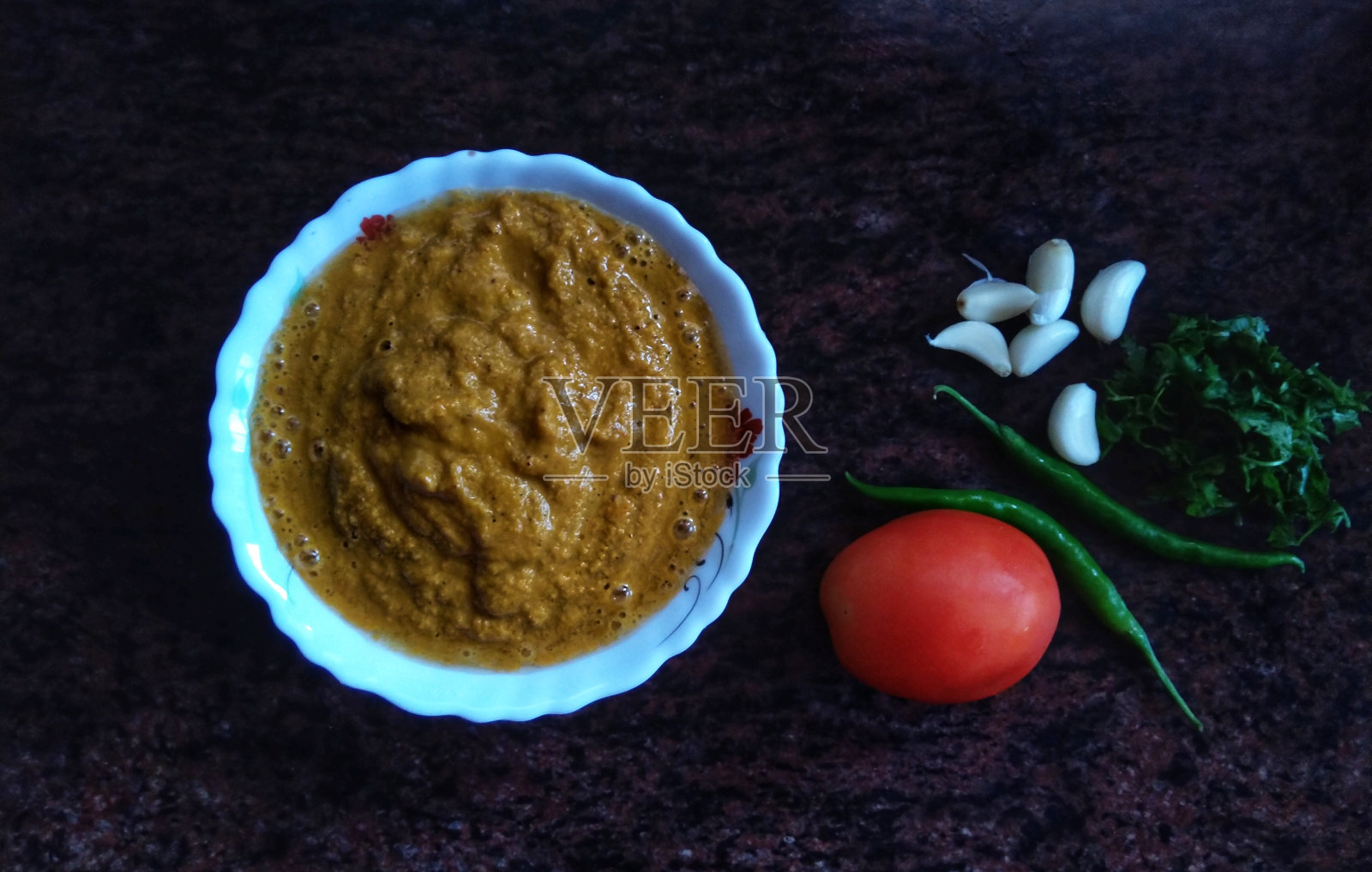 Kokani(印度马哈拉施特拉邦的西高山地区)风格的鱼椰子咖喱酱，这是食材;西红柿，辣椒，大蒜和香菜。照片摄影图片