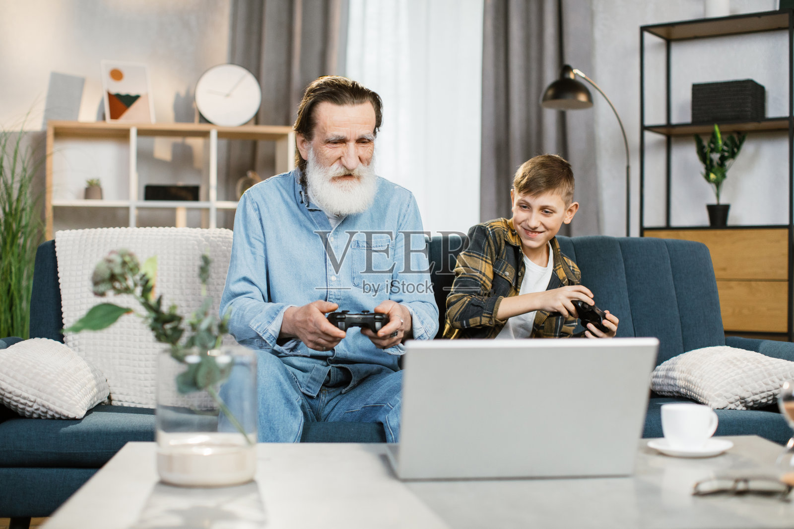 微笑的学龄男孩为他可爱的微笑的祖父母展示了新的游戏照片摄影图片