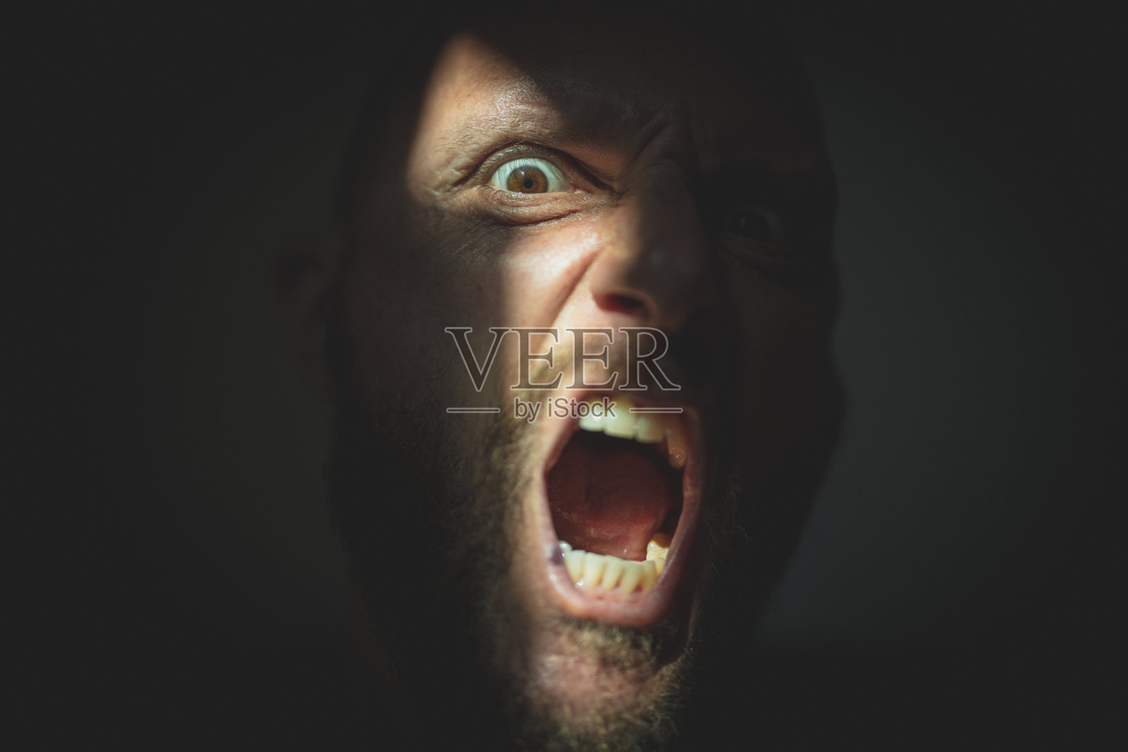 戏剧性的灯光肖像:可怕的男人在阴影中尖叫照片摄影图片