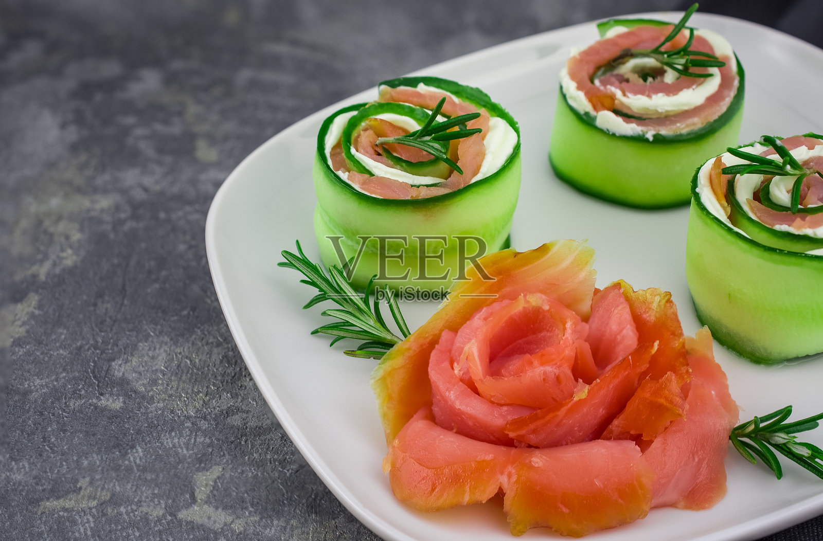 烟熏三文鱼配黄瓜和软奶酪卷放在白色的盘子里照片摄影图片