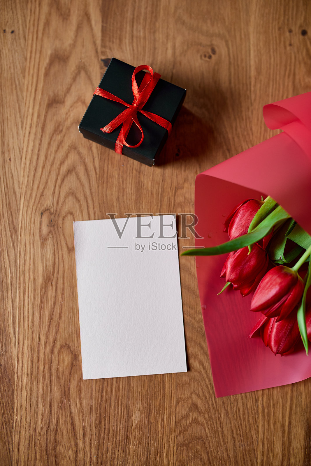 俯视图空卡与红色郁金香花在红色包装纸与礼盒，节日背景，快乐的母亲节，女人的一天，生日，3月8日，情人节的概念照片摄影图片