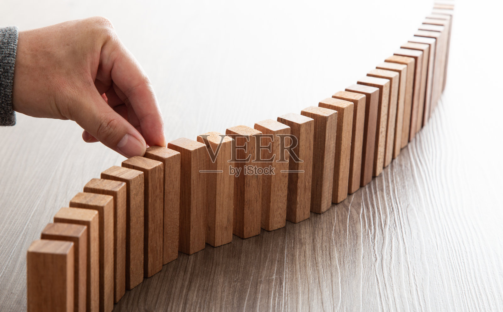 商业中的风险和战略，商人手在多米诺骨牌上放置木块的特写。照片摄影图片