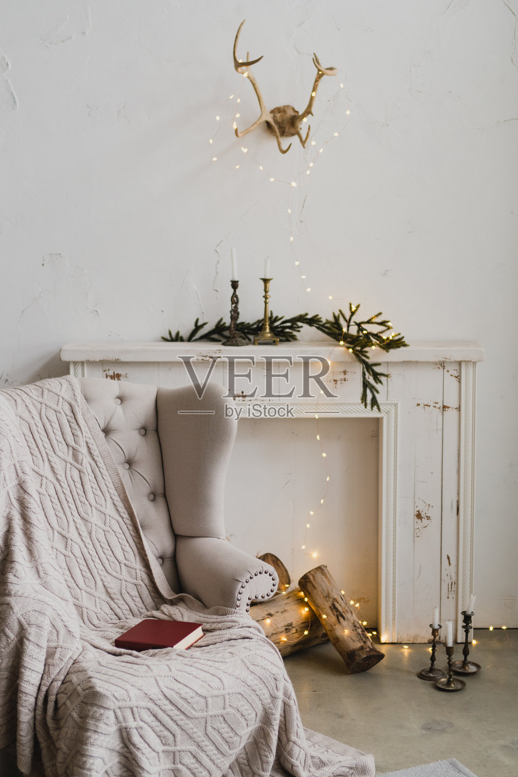 壁炉上的复古圣诞装饰。现代阁楼室内的蜡烛和书籍。照片摄影图片