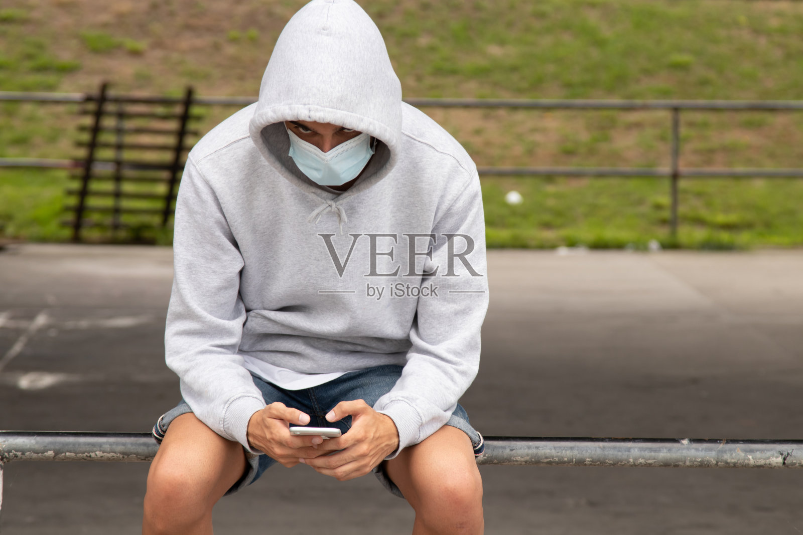 在城市里戴口罩和手机的年轻男人照片摄影图片