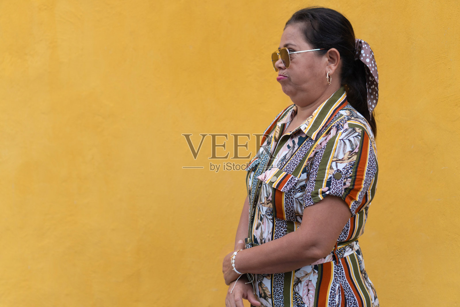 成熟的女人在黄色的墙前担心照片摄影图片