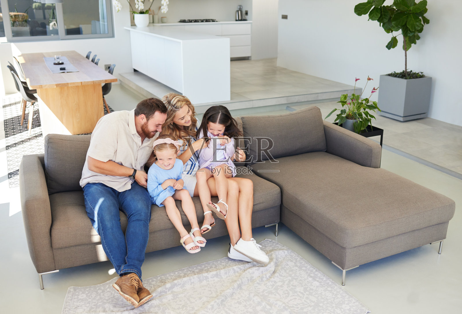 白人父母在家里的沙发上挠女儿痒痒照片摄影图片