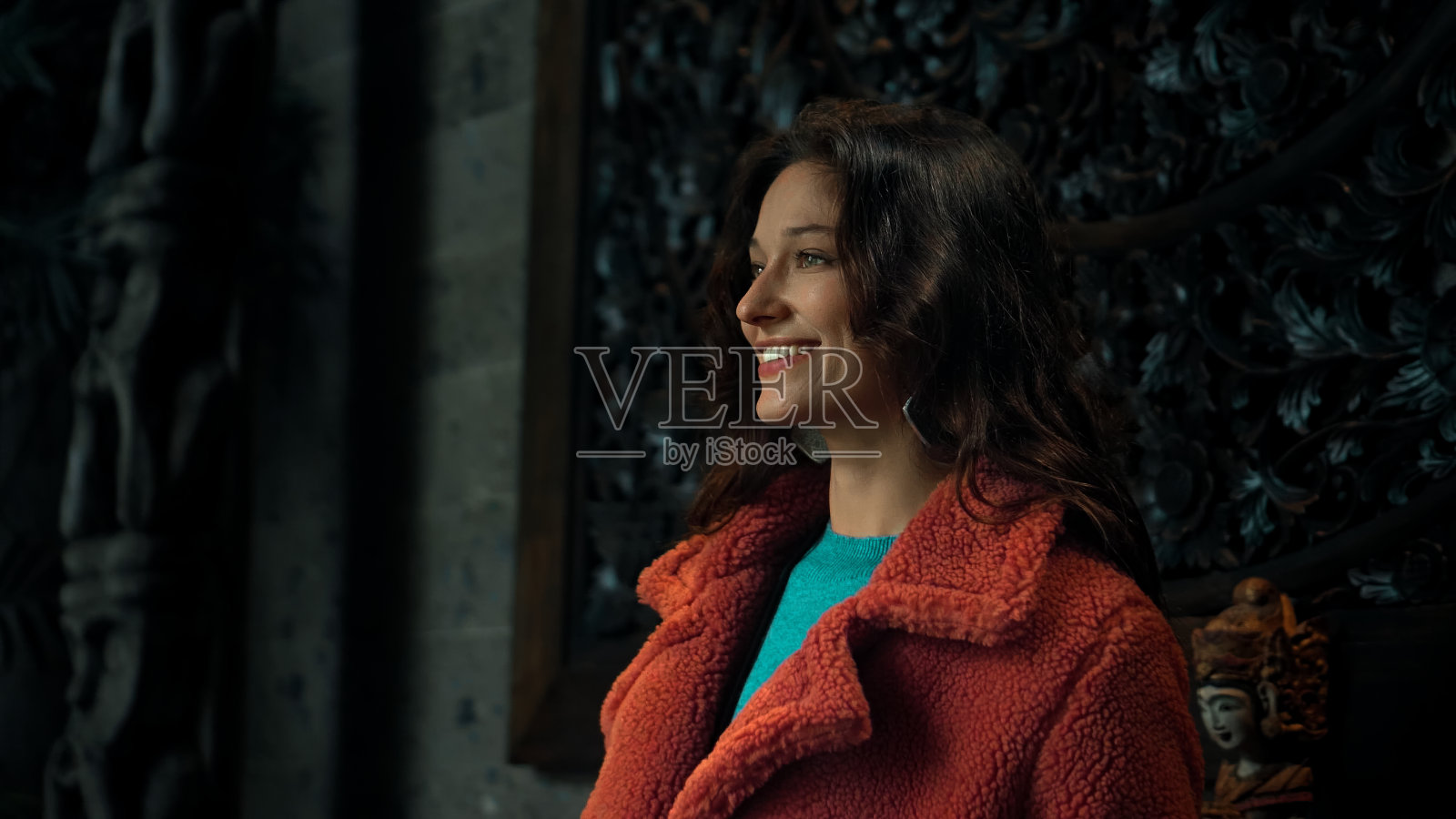 身着红色外套和蓝色毛衣的欧洲黑发女孩站在镜头前摆姿势照片摄影图片