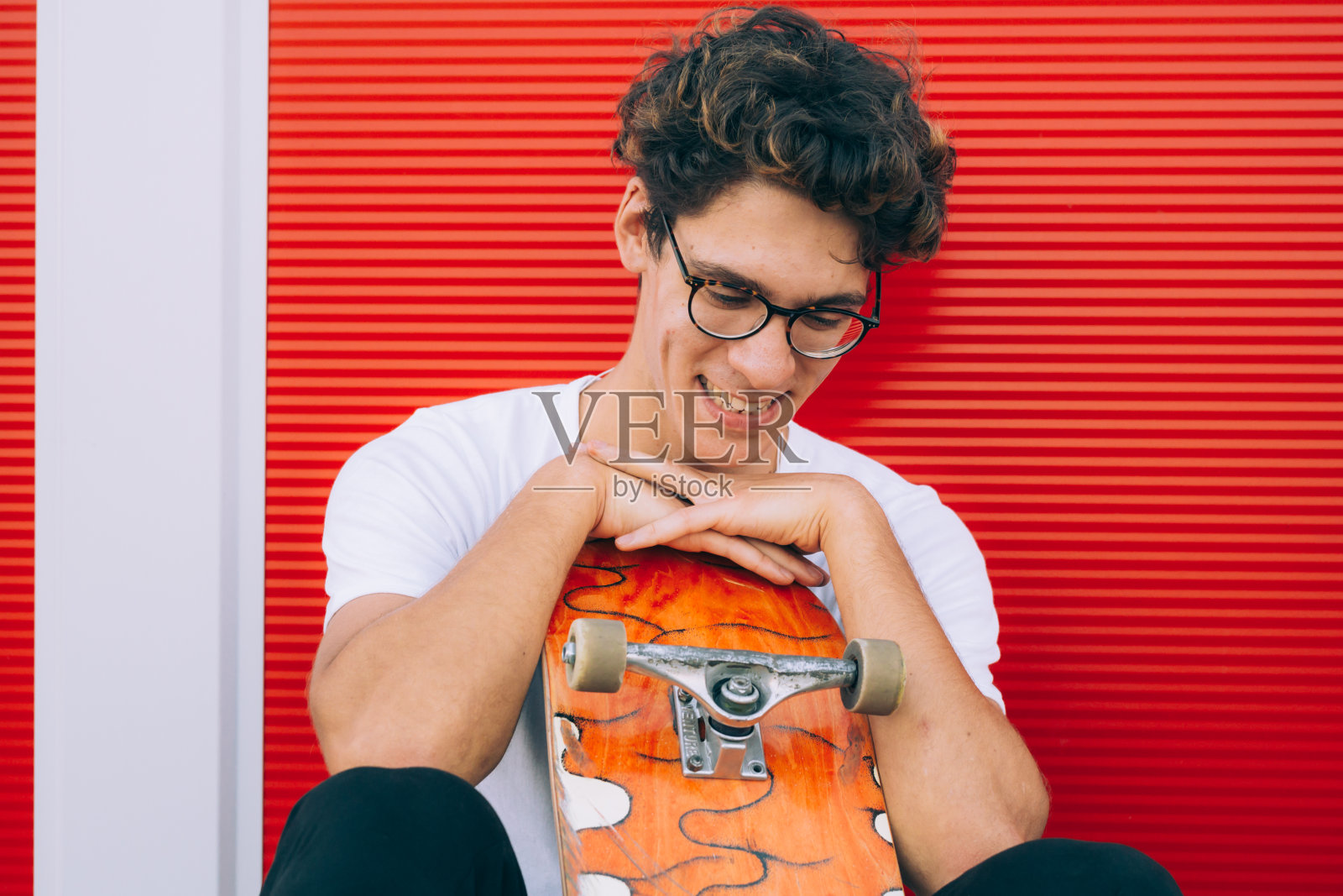 年轻的成年人与他的滑板摆姿势照片摄影图片