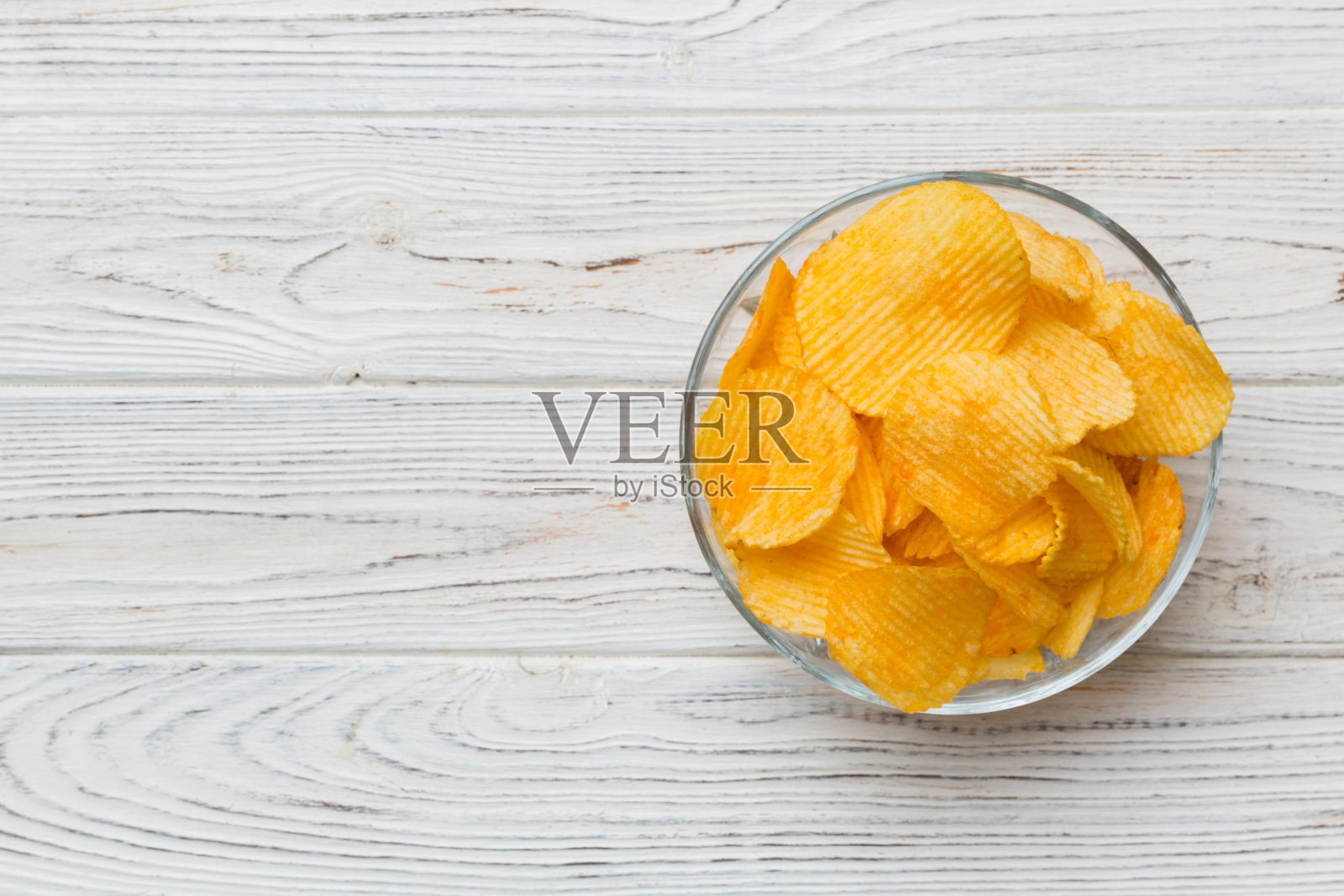 土豆片在碗上隔离的彩色背景。碗里的美味脆薯片。空间的文本。俯视图照片摄影图片