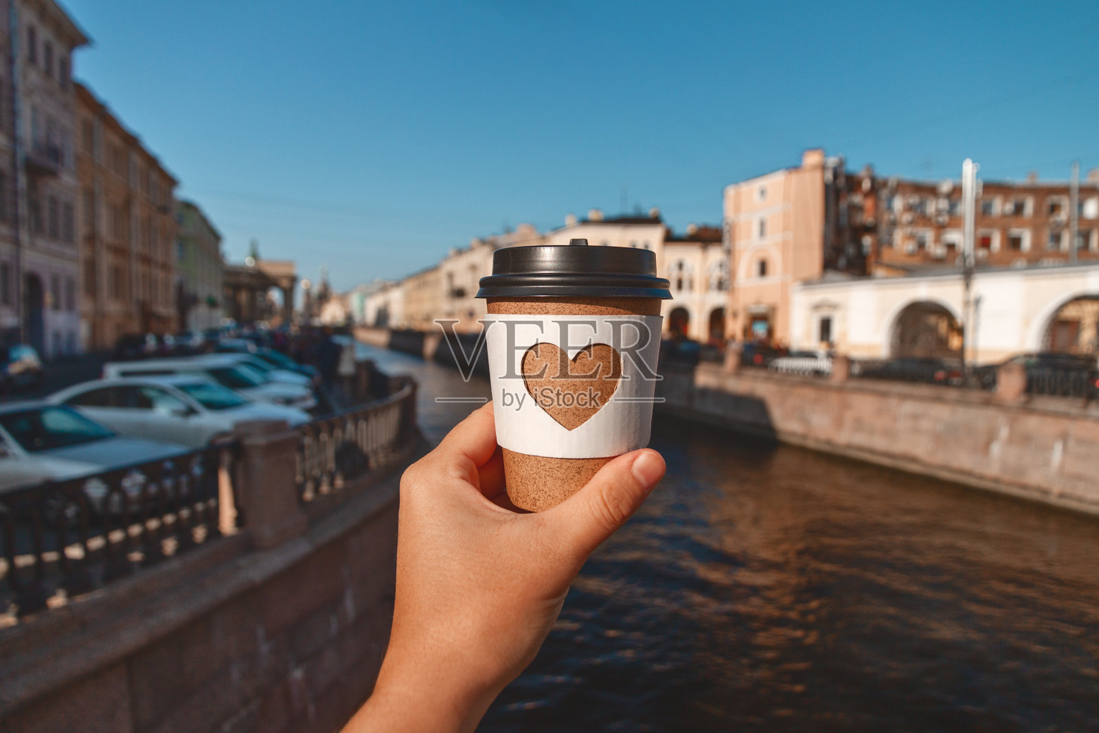 在圣彼得堡的河的背景上，女人的手掌上握着一杯天然咖啡照片摄影图片