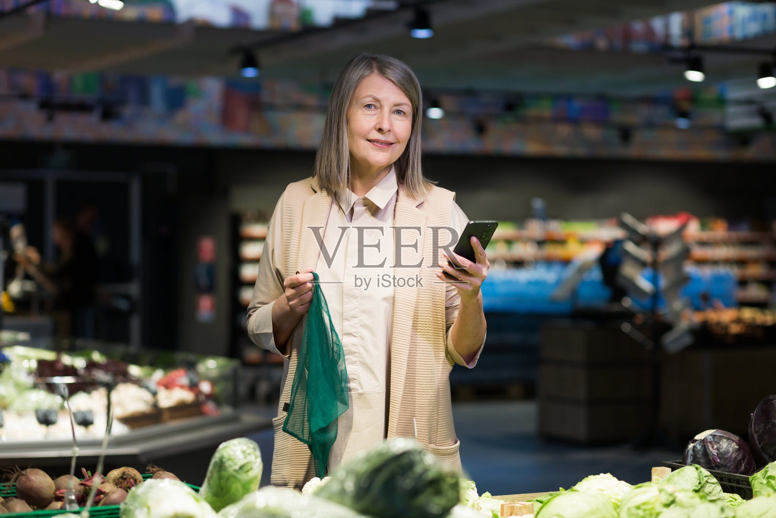 一位高级女士在超市挑选商品，看着手机上的电子清单照片摄影图片