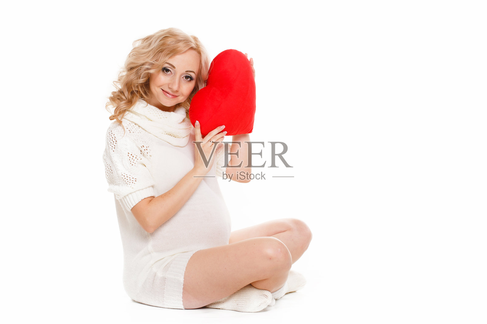 一个在白色背景下穿着白色短裙的孕妇。情人节照片摄影图片