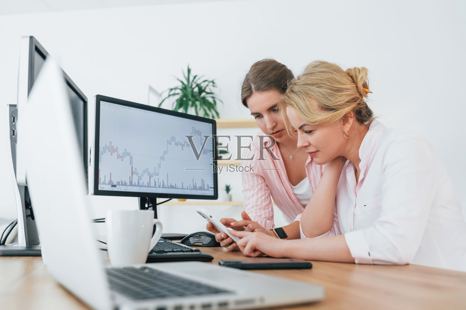 2名穿着正装的女证券经纪人正在电脑旁的办公室工作照片摄影图片