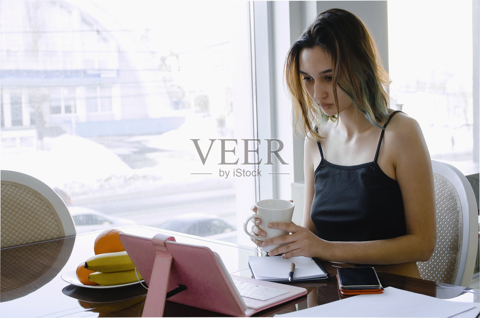 一个美丽的年轻女孩喝着茶，在家远程工作。照片摄影图片