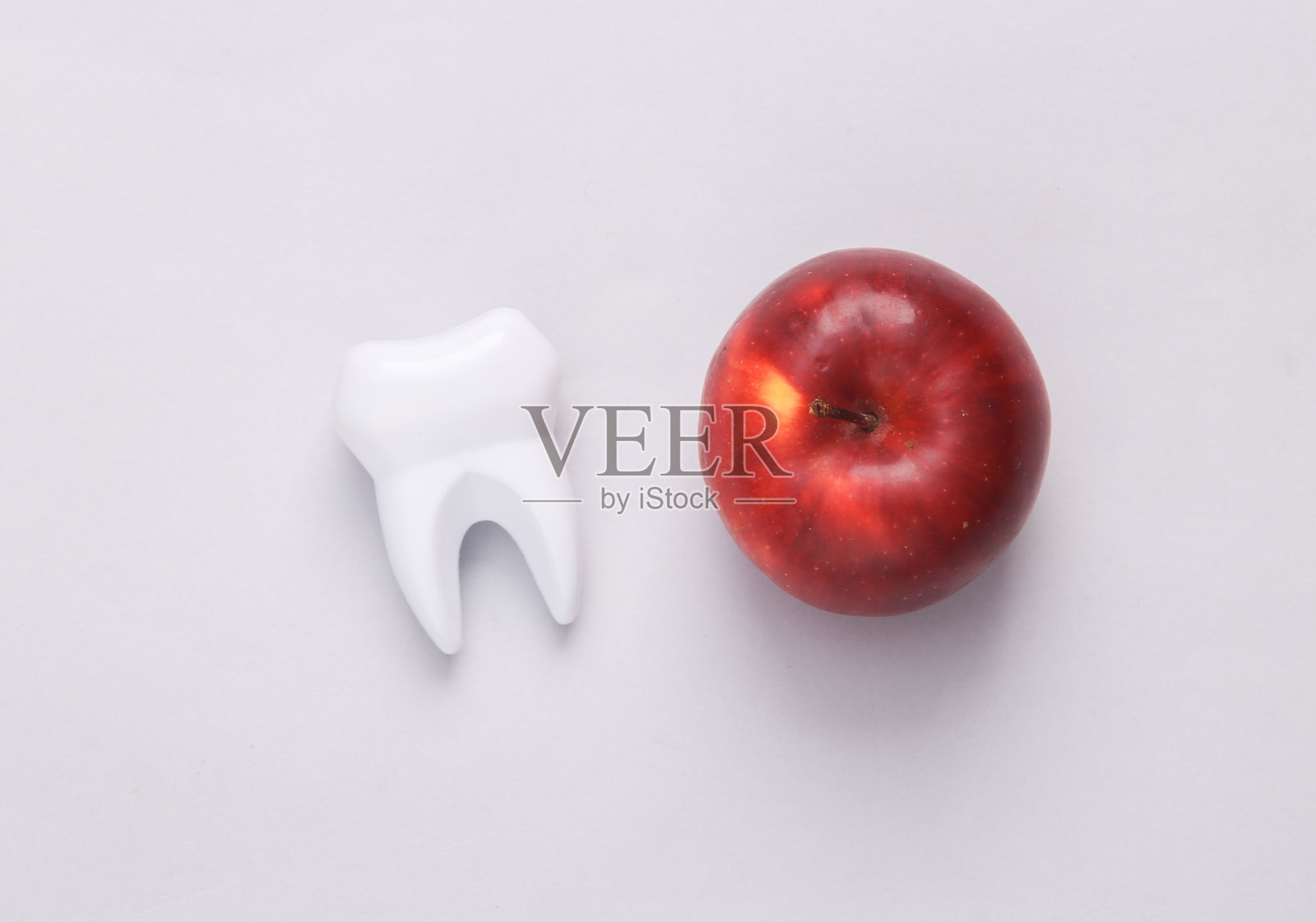 健康牙齿的概念。苹果和牙齿模型在灰色背景照片摄影图片