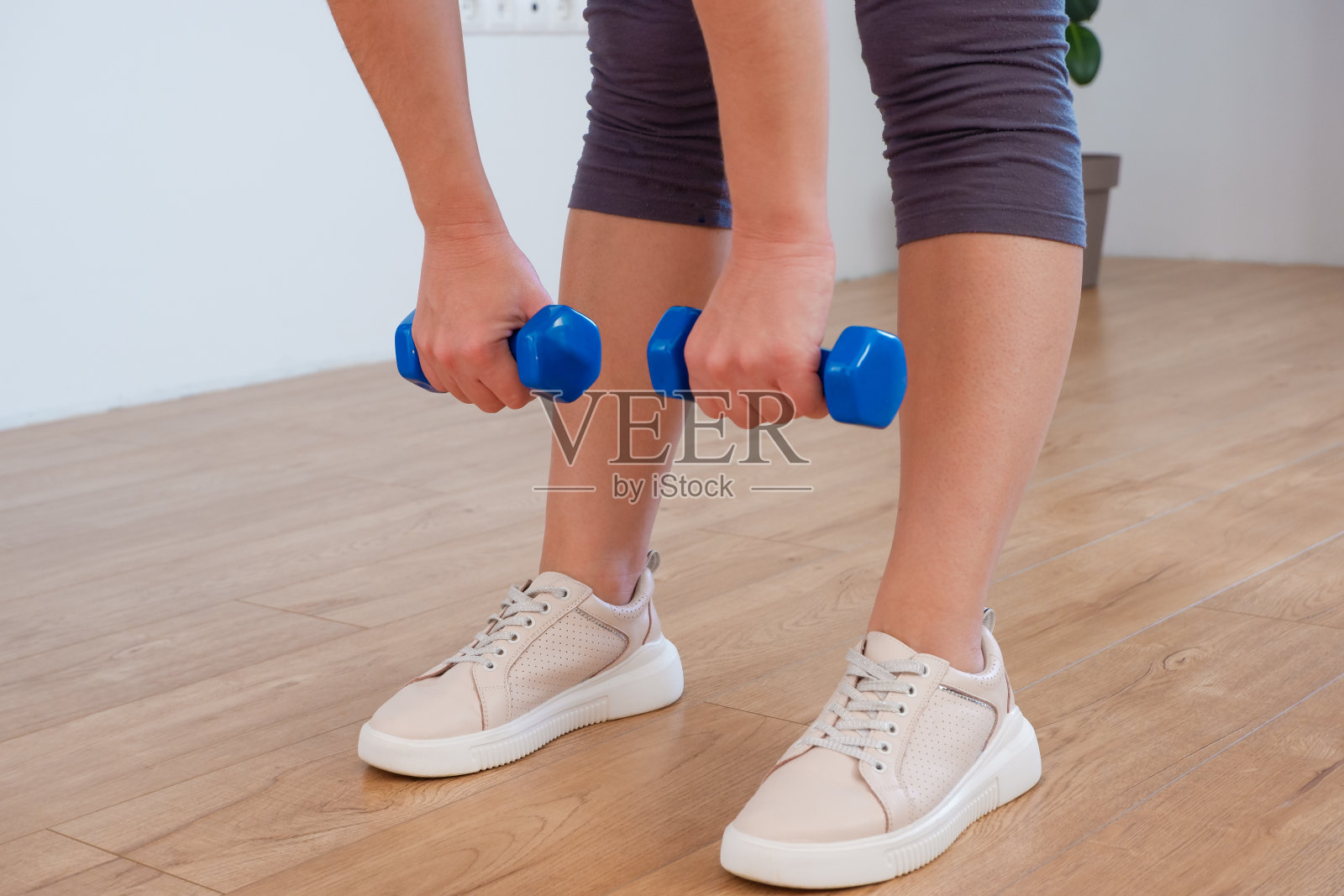 女运动员练习有氧哑铃。女人在家里举重和锻炼。照片摄影图片