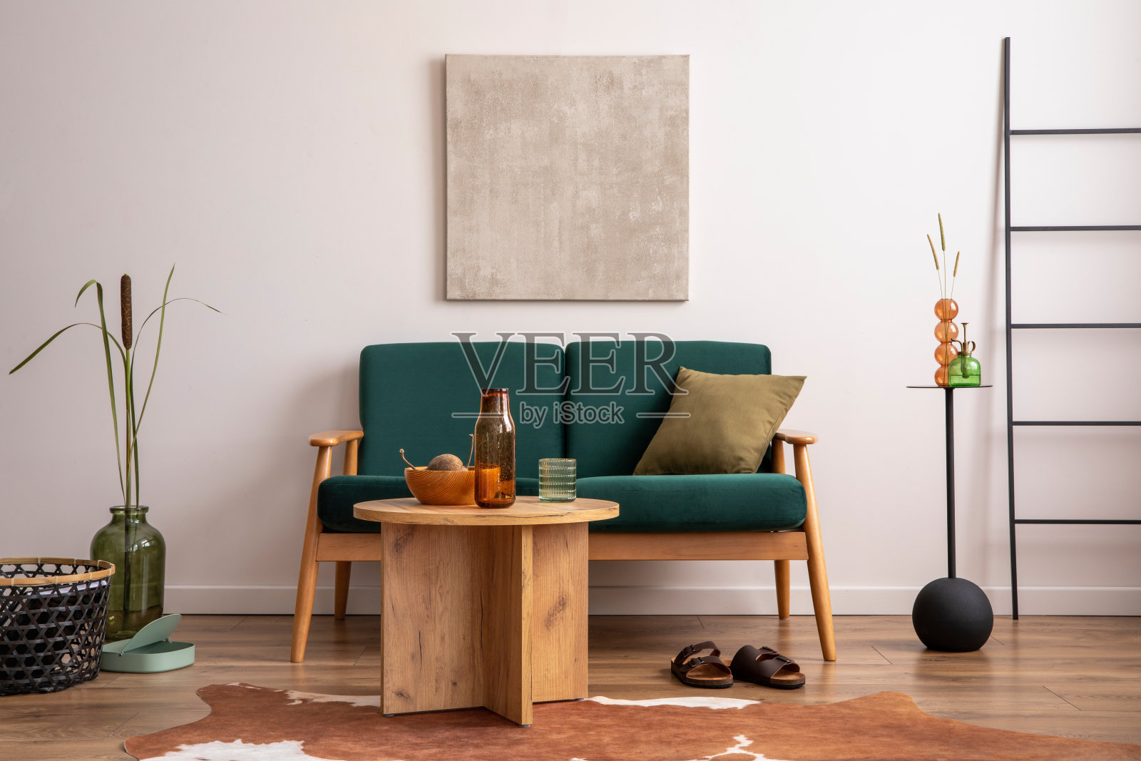 客厅的经典空间，有模拟海报框架，瓶绿色沙发，圆形木制咖啡桌，花瓶里的干花，地毯和个人配饰。米色墙。家居装饰。模板。照片摄影图片