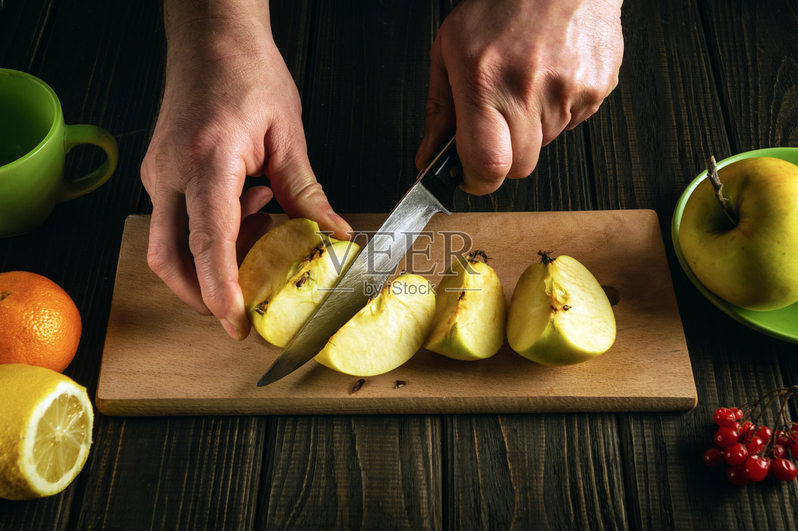 在家制作苹果果盘或水果饮料。厨师用刀在砧板上切新鲜苹果的手照片摄影图片