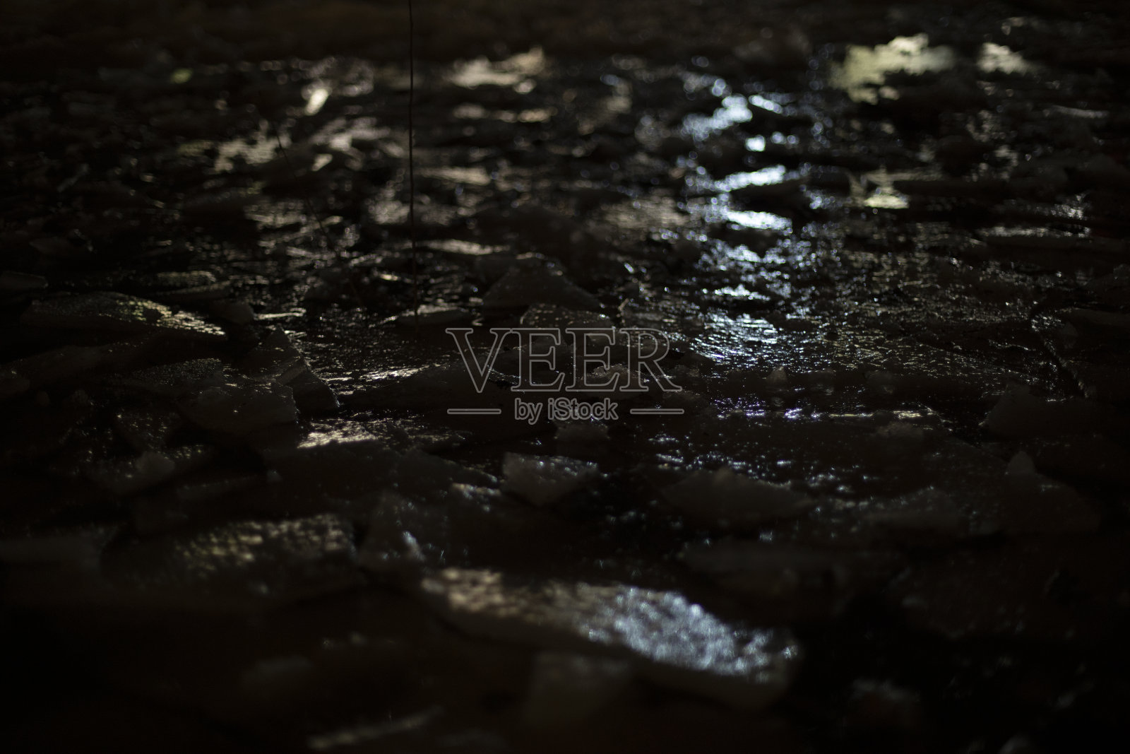 黑暗中灯光在冰上。人造光在冰冻水面上的反射。照片摄影图片