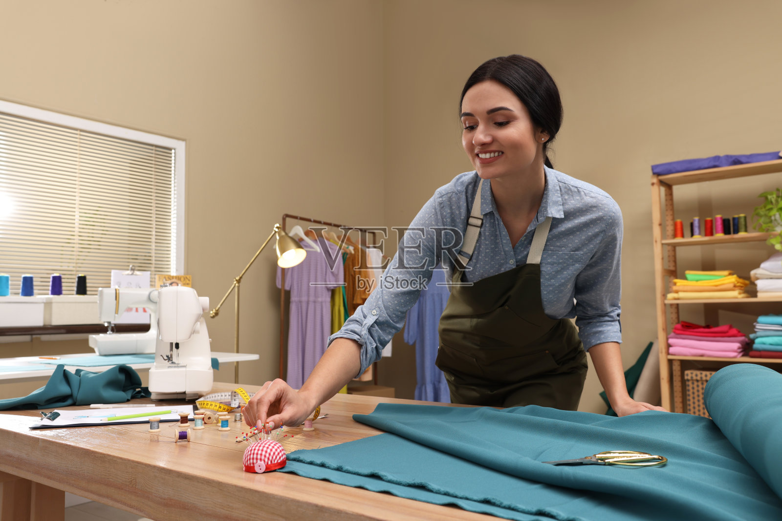 裁缝在车间从垫子上取别针照片摄影图片