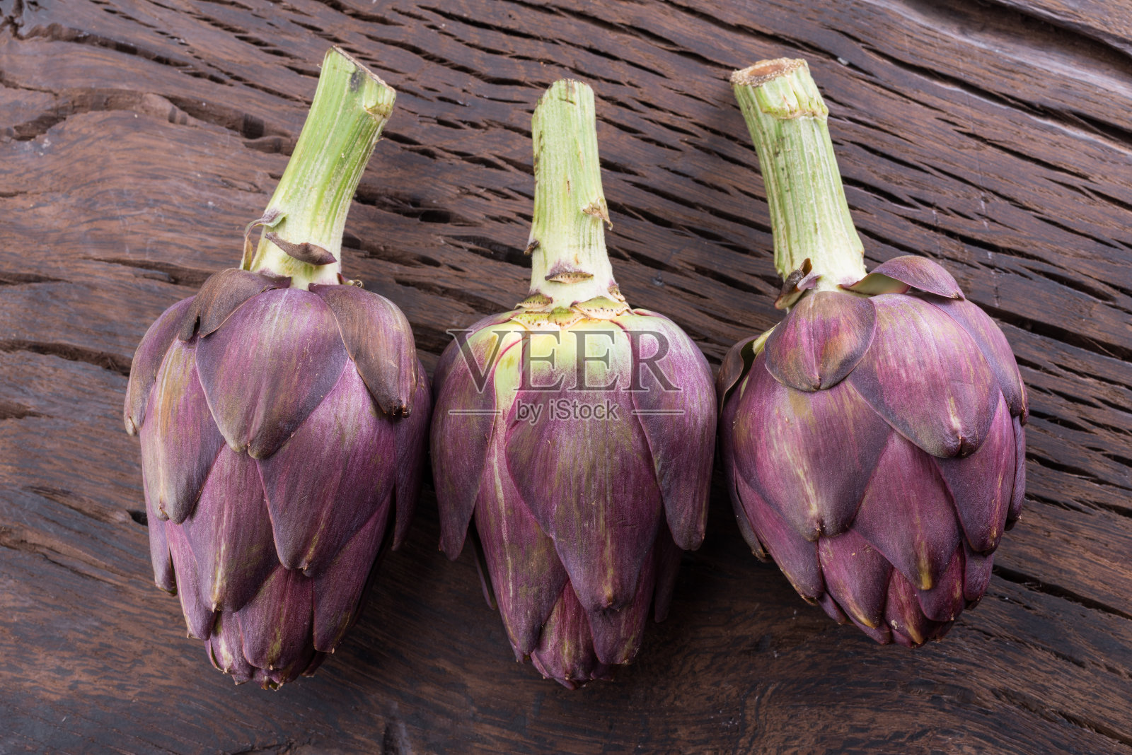 绿色和紫色的洋蓟花可食用芽在木制背景。照片摄影图片