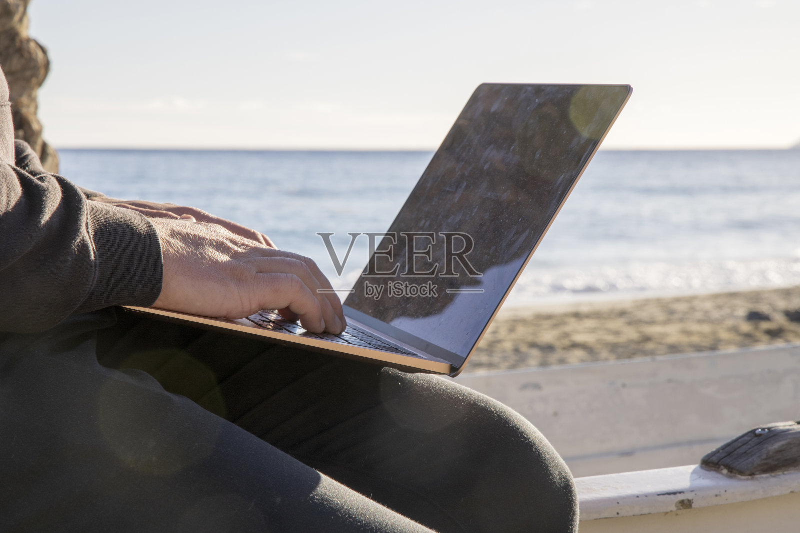 近距离的年轻人在笔记本电脑上工作，在海滩上照片摄影图片